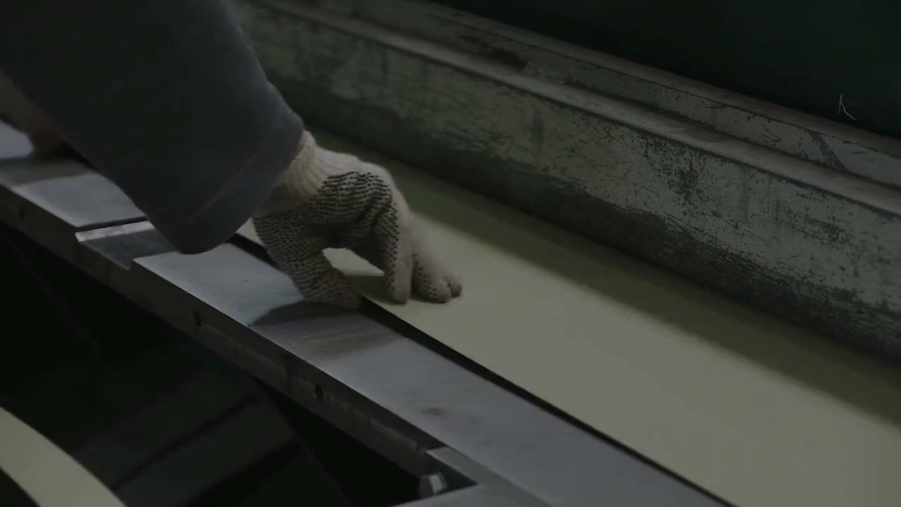 Gloved hands set a painted sheet in the folder